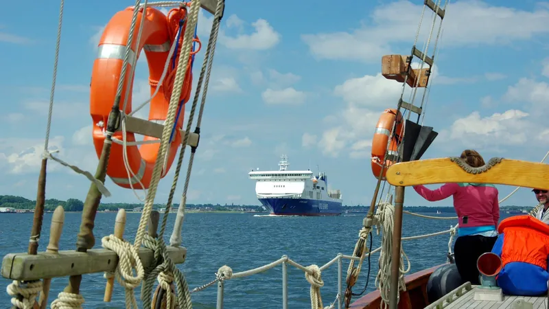 Fähre Athena Seaways am Horizont, im Vordergrund Takelage und Rettungsring eines Segelschiffs
