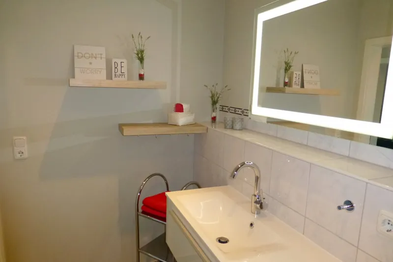 Waschbecken mit Ablageboard, Spiegel und roten Handtüchern