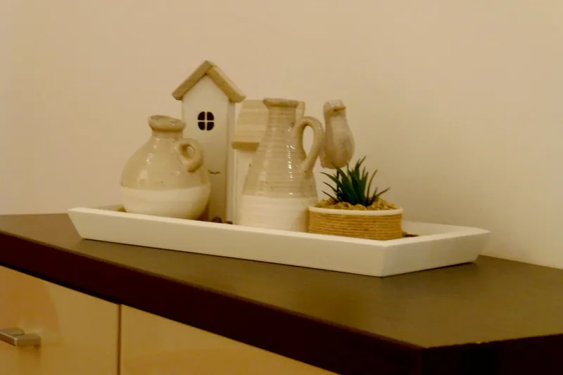 Keramik-Dekoration mit kleinem Haus und Kannen auf einem Sideboard