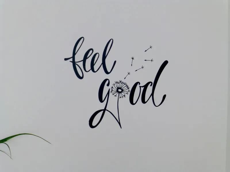 Handgeschriebener Schriftzug „feel good“ mit Pusteblume an einer hellen Wand