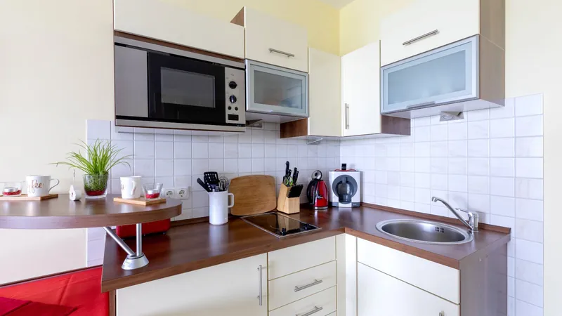Helle Küchenschränke mit Einbau-Mikrowelle über der Arbeitsfläche mit Kaffeemaschine und Messerblock