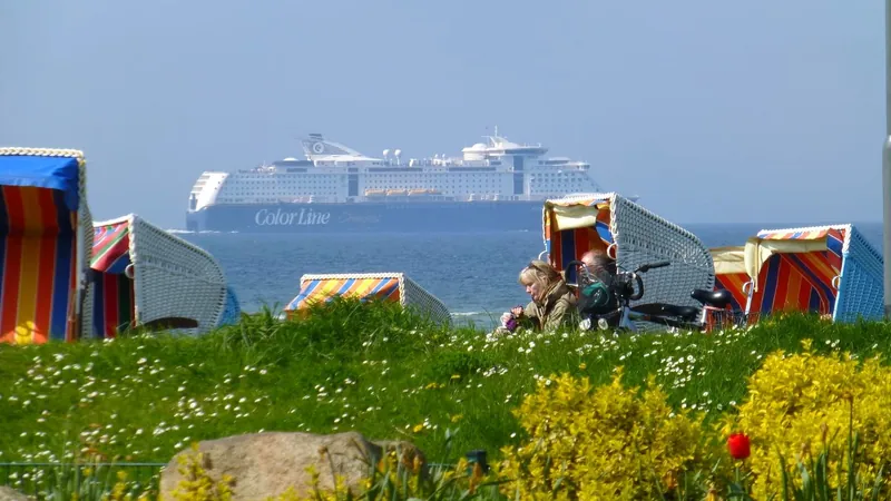 Großes Passagierschiff auf der Ostsee vor Stein, davor Strandkörbe am Deich