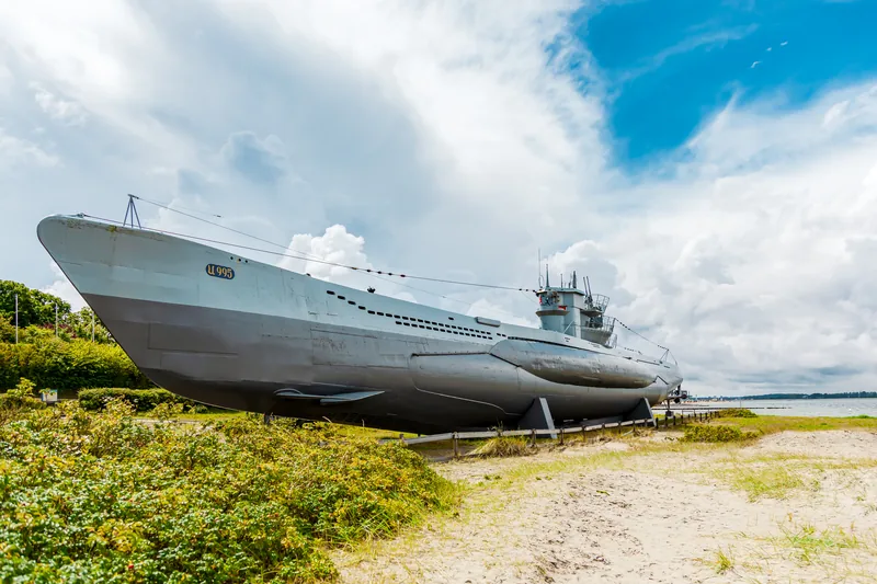 Museums-U-Boot U 995 auf dem Strand von Laboe zwischen Dünengrün und Sand, darüber Wolken und blauer Himmel